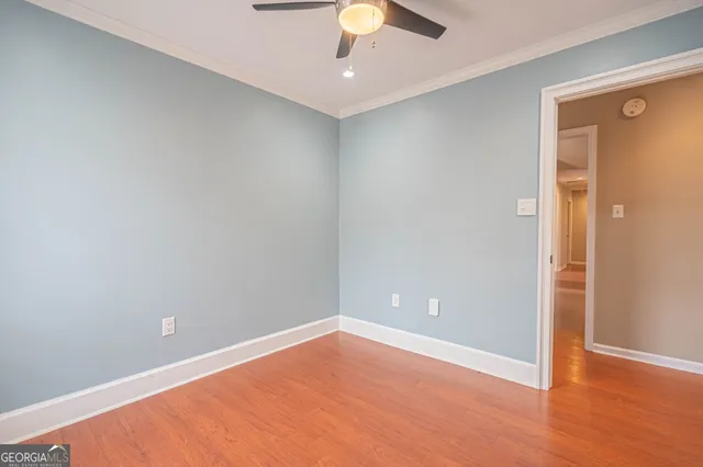 an empty room with wooden floor and ceiling fan