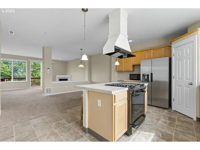 a kitchen with stainless steel appliances kitchen island granite countertop a sink a microwave a refrigerator and white cabinets