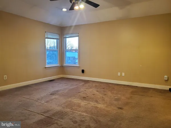 an empty room with windows and chandelier fan