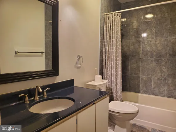 a bathroom with a granite countertop sink toilet a mirror a bathtub and shower