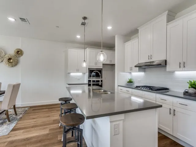 a kitchen with kitchen island granite countertop a sink a counter space appliances and cabinets