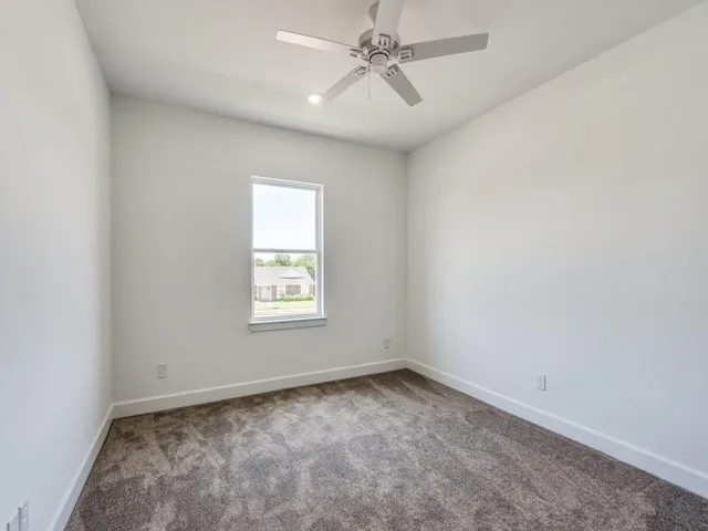 an empty room with a window and a fan