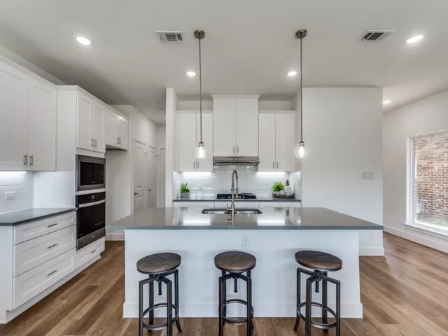 a kitchen with granite countertop white cabinets and stainless steel appliances