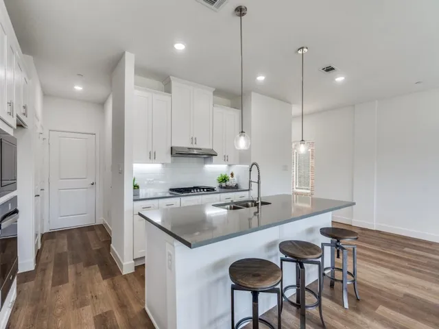 a kitchen with stainless steel appliances granite countertop a sink a stove a refrigerator and chairs