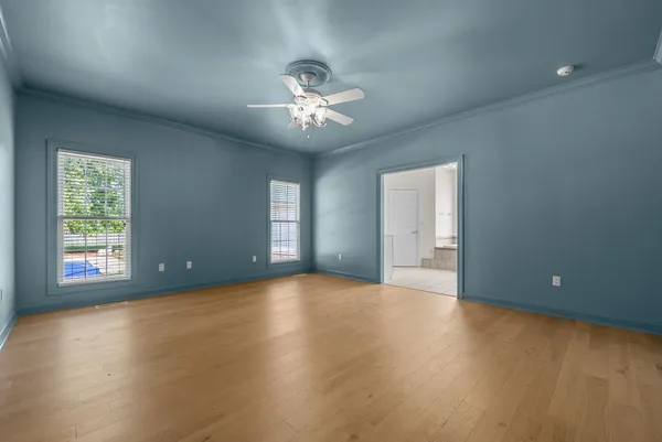 an empty room with windows and ceiling fan