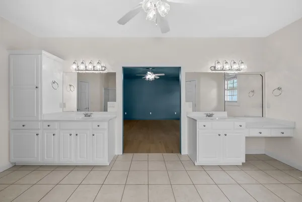 a view of an empty room with chandelier fan and a window