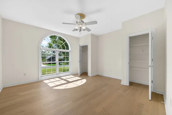 an empty room with wooden floor and fan