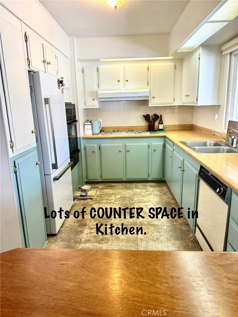 4650 Dulin Road, Unit 11 Fallbrook, CA 92003 - Photo 16 of 38 a kitchen with stainless steel appliances granite countertop a refrigerator a stove and white cabinets with wooden floor
