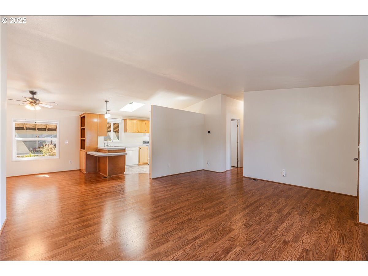 1819 Southeast Orient Drive, Unit 1 Gresham, OR 97080 - Photo 7 of 31 a view of an empty room with wooden floor and a kitchen