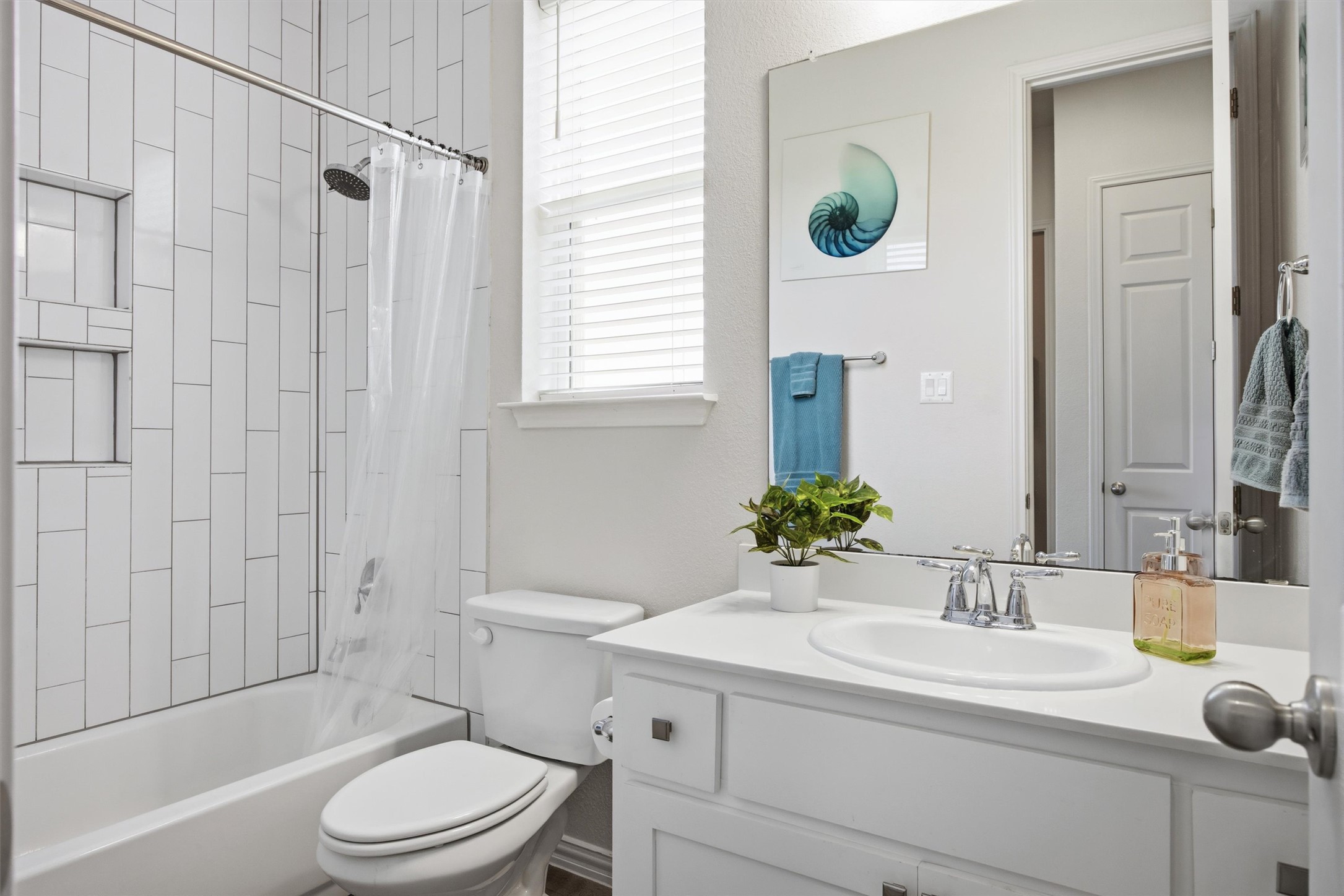 192 Raptor Beak Way Cedar Creek, TX 78612 - Photo 24 of 38 Full bathroom featuring a white tub with subway tile surround, integrated shower niches, a single vanity with a white countertop, and a large wall-mounted mirror
