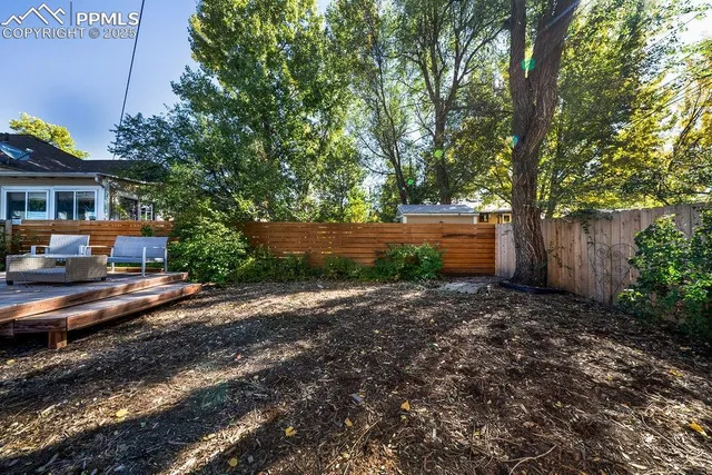 a backyard of a house with wooden fence and a tree