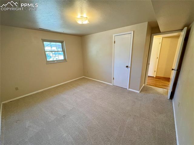 280 Raven Hills Road Colorado Springs, CO 80919 - Photo 36 of 48 Unfurnished bedroom with carpet floors, baseboards, a textured ceiling, and visible vents