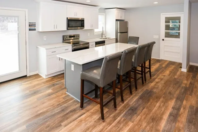 a kitchen with stainless steel appliances kitchen island granite countertop a table chairs and a refrigerator