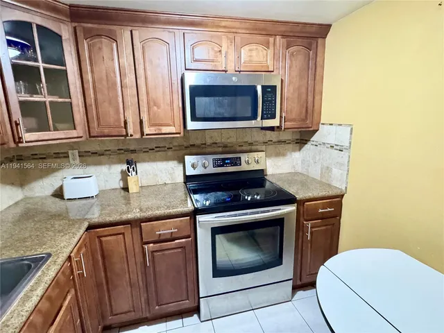 a kitchen with granite countertop a sink a stove and cabinets