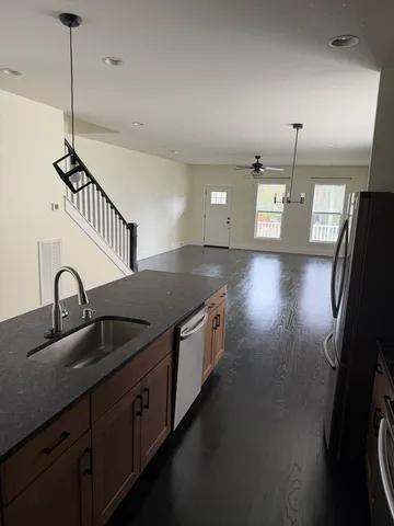 a kitchen with stainless steel appliances granite countertop a sink a stove and a wooden floor