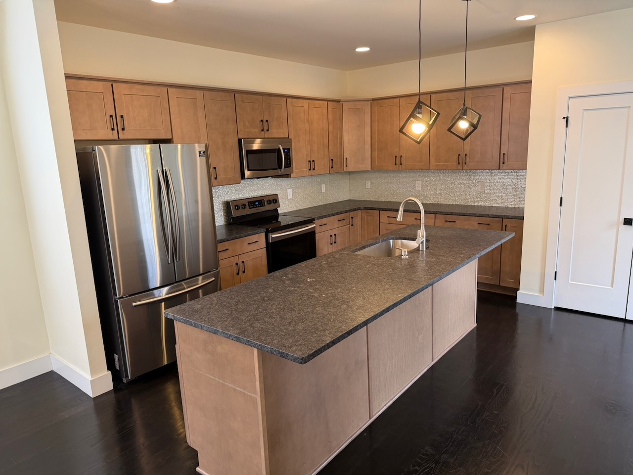 a kitchen with stainless steel appliances granite countertop a refrigerator a sink dishwasher a stove and a refrigerator with wooden floor