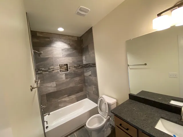 a bathroom with a granite countertop sink toilet and shower