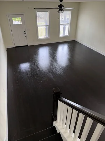 a view of an empty room with wooden floor and a window