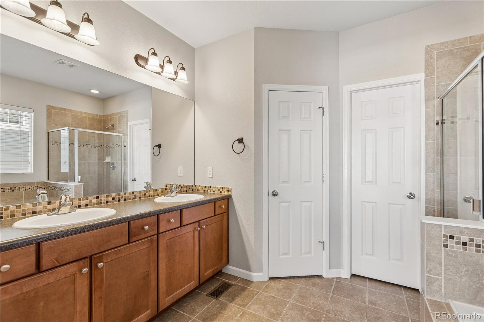 5031 South Rome Street Aurora, CO 80015 - Photo 17 of 39 a spacious bathroom with a double vanity sink a mirror and a