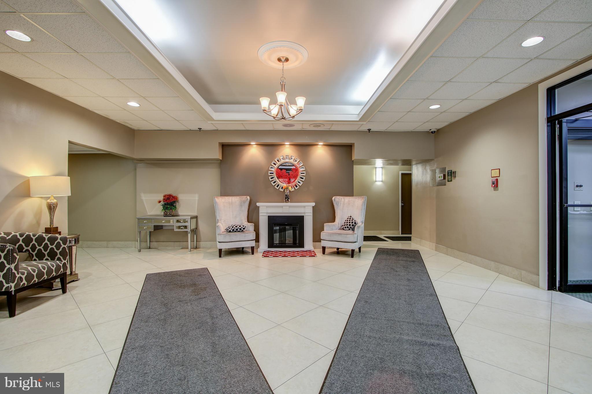 5911 Edsall Road, Unit 902 Alexandria, VA 22304 - Photo 2 of 26 a living room with furniture a fireplace and a chandelier