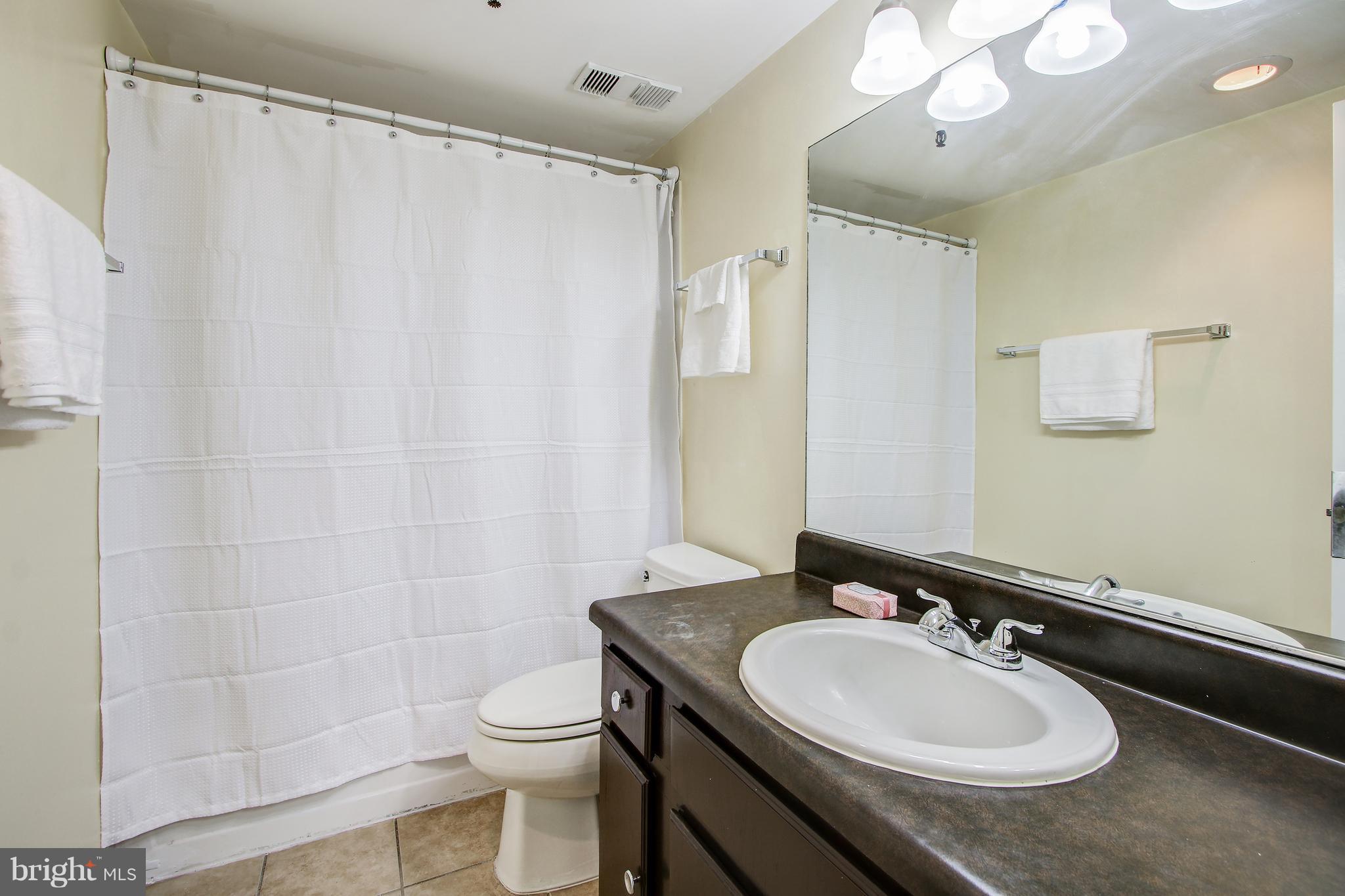 5911 Edsall Road, Unit 902 Alexandria, VA 22304 - Photo 22 of 26 a bathroom with a sink toilet a mirror and shower curtain
