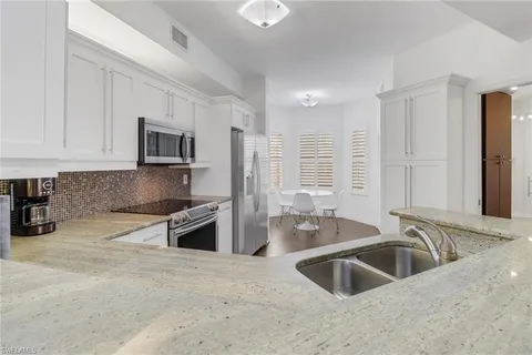 a kitchen with kitchen island granite countertop a sink stainless steel appliances and cabinets