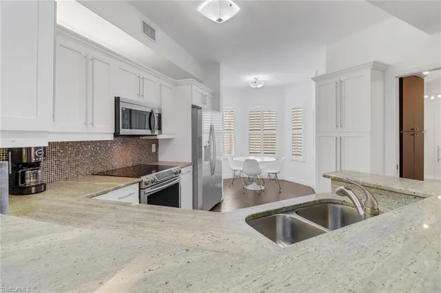 a kitchen with kitchen island granite countertop a sink stainless steel appliances and cabinets