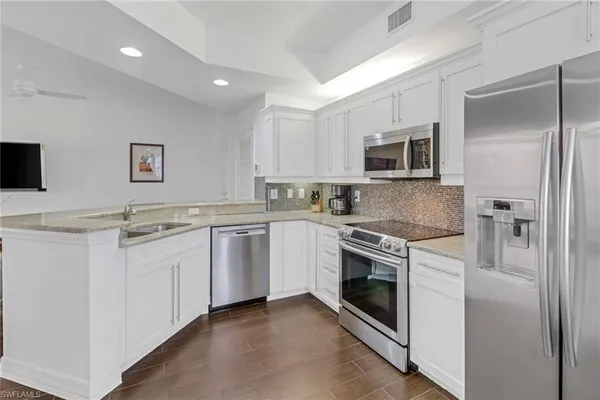 a kitchen with granite countertop white cabinets and stainless steel appliances