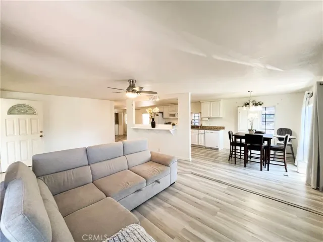 a living room with furniture wooden floor and kitchen view