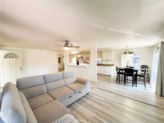 a living room with furniture wooden floor and kitchen view