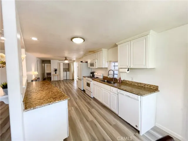 a large white kitchen with sink and cabinets