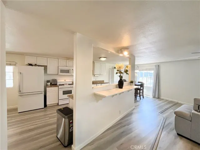 a large white kitchen with cabinets wooden floor and a refrigerator
