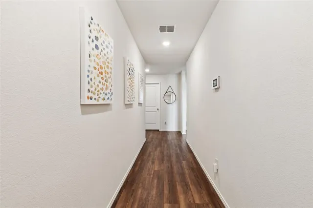a view of a hallway with wooden floor and a bathroom