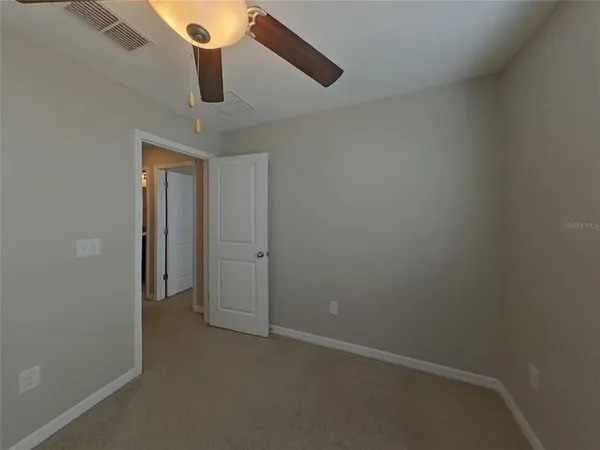 an empty room with a ceiling fan and window