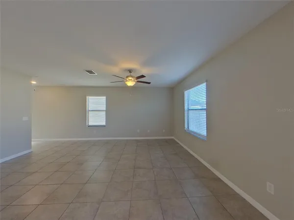 an empty room with windows and fan