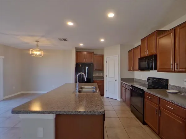 a kitchen with stainless steel appliances granite countertop a sink a stove counter space and cabinets
