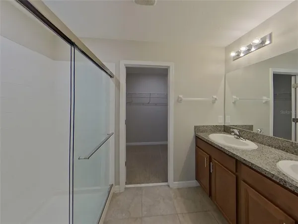 a bathroom with a granite countertop sink a mirror and a shower