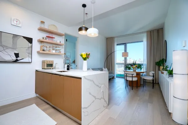 a living room with stainless steel appliances granite countertop furniture a couch and a chandelier