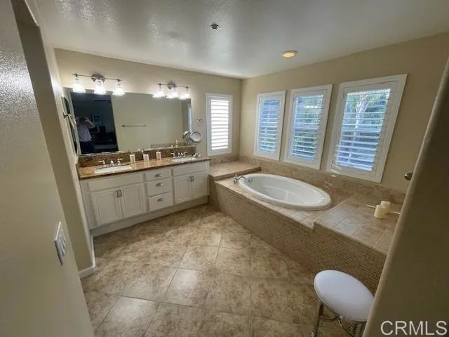 a bathroom with a granite countertop sink a mirror and a bathtub