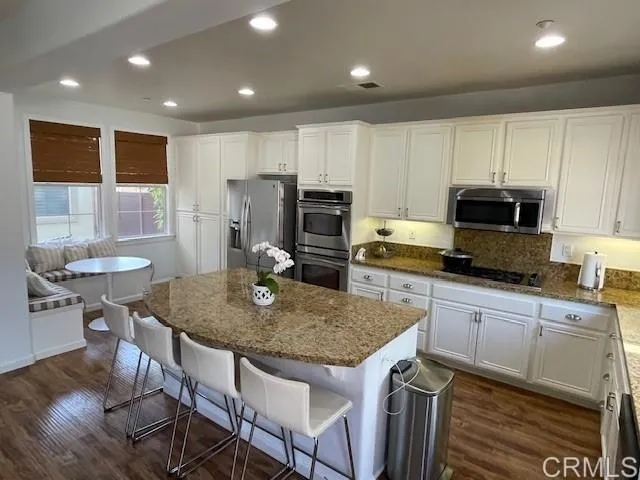 a kitchen with a stove a sink a microwave a dining table and chairs