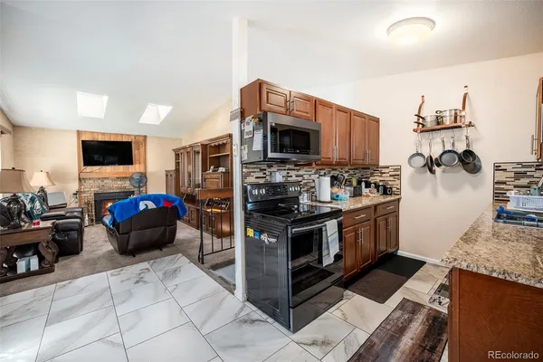 a kitchen with stainless steel appliances granite countertop a stove top oven a sink a dining table and chairs