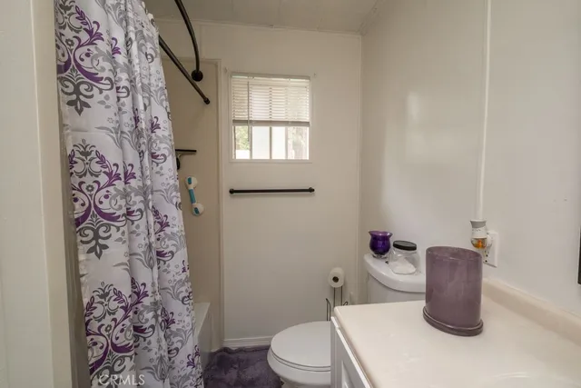 a bathroom with a toilet sink and shower curtain