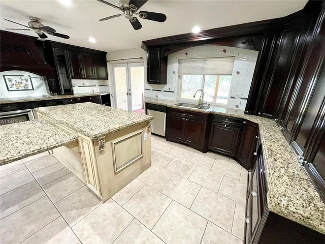 a kitchen with stainless steel appliances kitchen island granite countertop a sink stove and cabinets