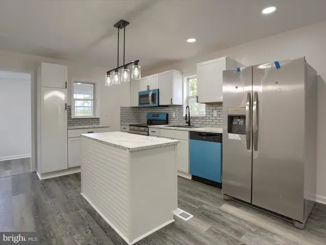 a kitchen with granite countertop a sink stainless steel appliances and white cabinets