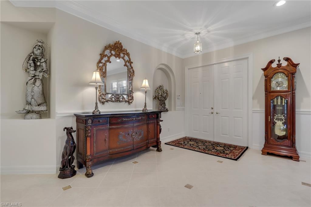 Entrance foyer with ornamental molding, wainscoting, and tile patterned floors