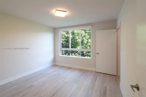 a view of an empty room with wooden floor and closet