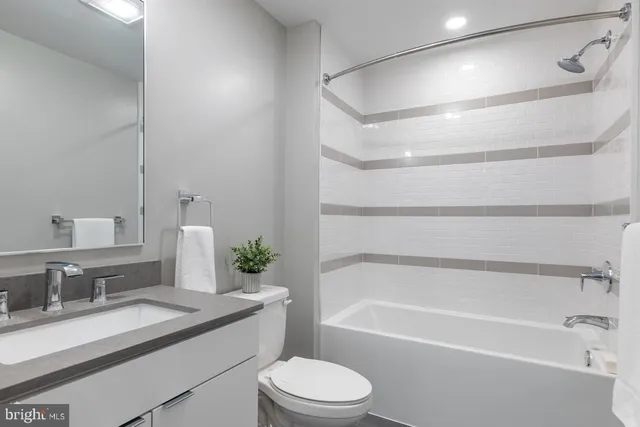 a bathroom with a bathtub shower sink vanity mirror and toilet