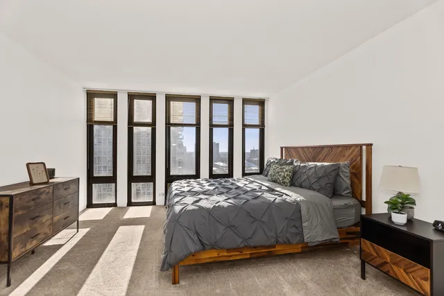 a bedroom with a bed and a dresser next to a window