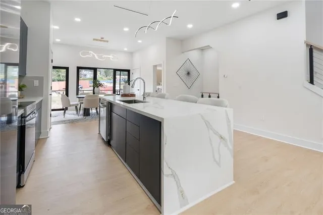 an open kitchen with kitchen island a stove a sink a refrigerator and windows