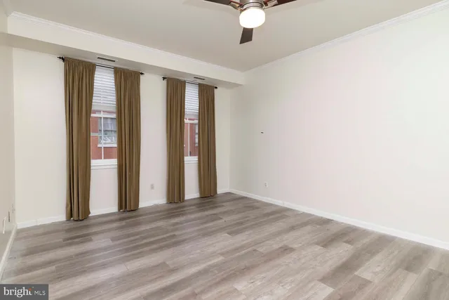 an empty room with wooden floor and fan